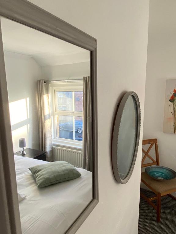 a mirror in a bedroom with a bed and a window at Ashington Home from Home in Ashington