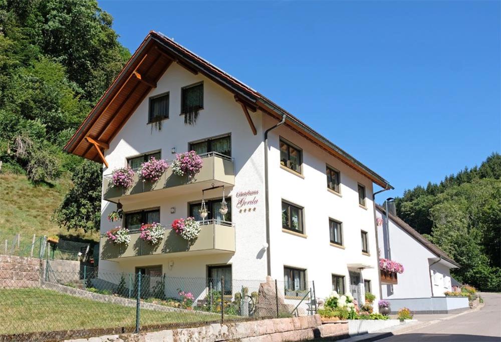 ein weißes Gebäude mit Blumen auf den Balkonen in der Unterkunft Gästehaus Gerda in Bad Peterstal-Griesbach