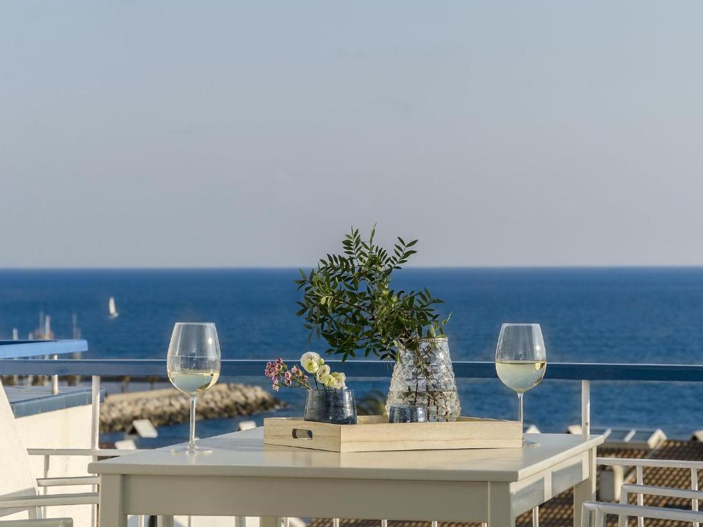 a table with two wine glasses and flowers on a balcony at Sitges Spaces Sea View Paradise- 2 Bedrooms, 2 Bathrooms, Terrace, Amazing Sea Views in Sitges