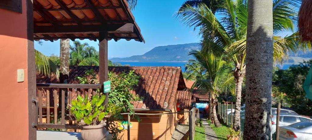 a view of a house with palm trees and the ocean at Pousada Por do Sol in Ilhabela