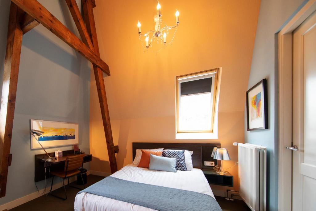 een slaapkamer met een bed en een kroonluchter bij Hotel De Villa in Dongen