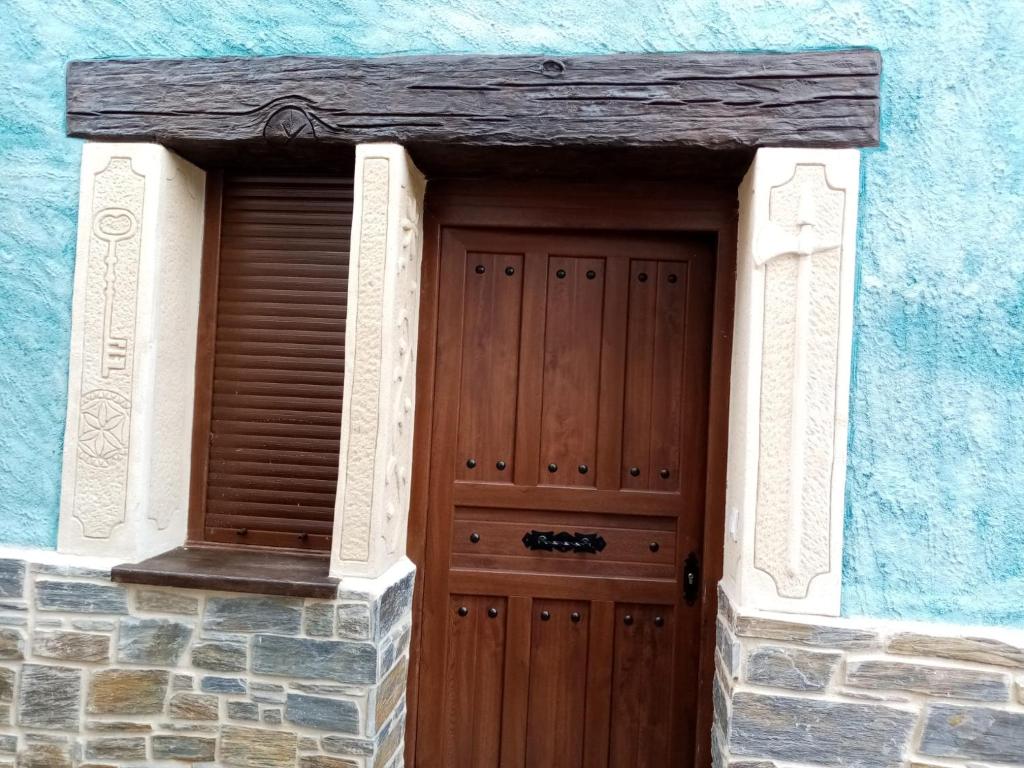 uma porta de madeira num edifício azul em Casa Rural Abuelo Flore em Caminomorisco