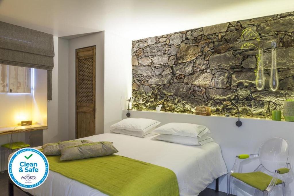 a bedroom with a bed and a stone wall at Graviana - Pedra Lima Charming House in Lagoa