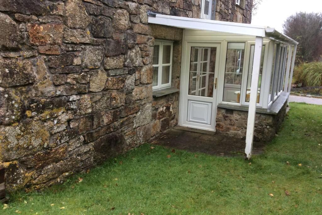 - un bâtiment en pierre avec une porte et une fenêtre dans l'établissement Okewoon Barn, à Lanivet
