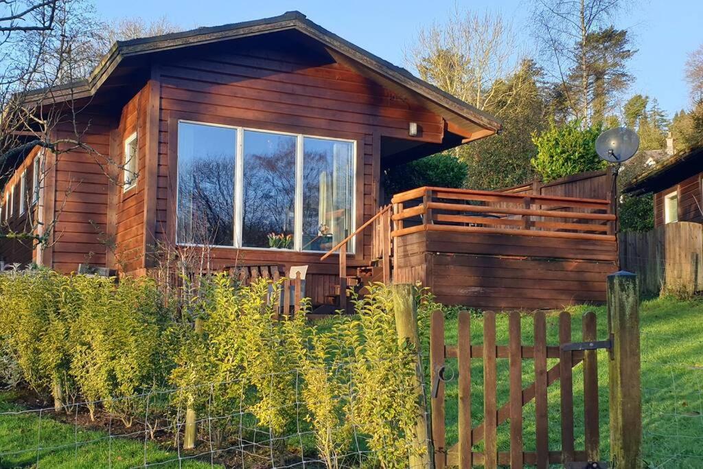 a log cabin with a fence in front of it at Luxurious lodge, Hot tub at Rudyard Lake, couples or small family in Rudyard