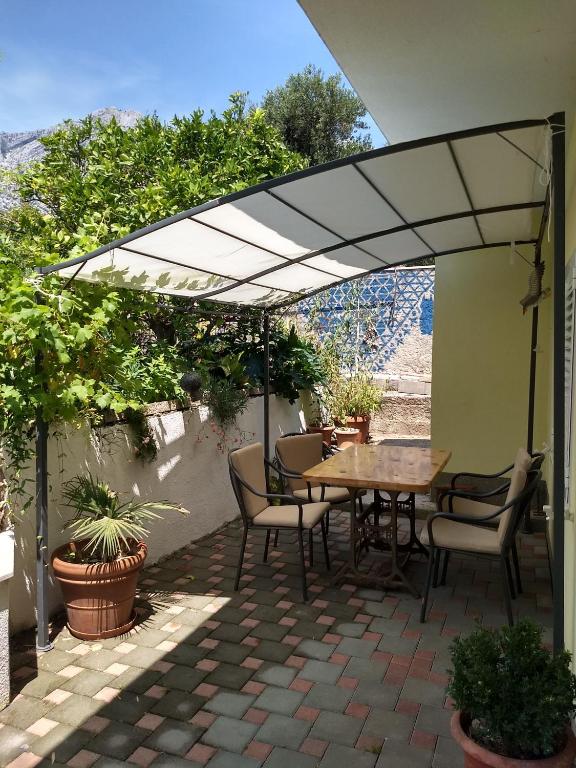 a patio with a table and chairs under an umbrella at Spacious garden house, Orebić (4+1) in Orebić