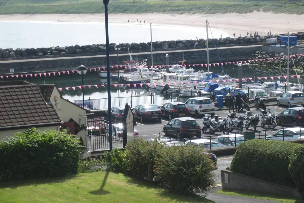 a parking lot with cars and motorcycles and a beach at 2 bed house at Ballycastle seafront in Ballycastle