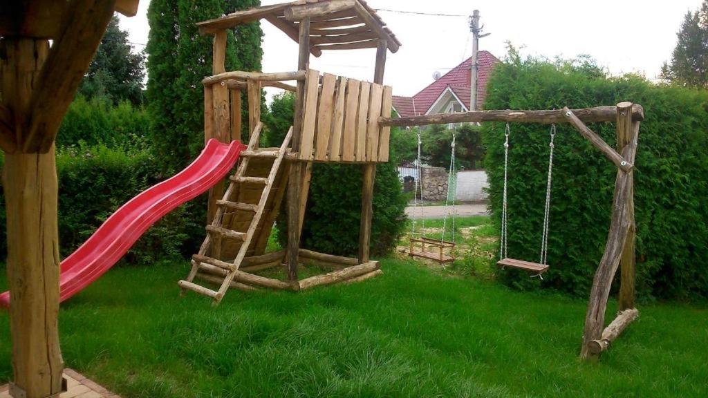 a wooden playground with a red slide and swings at Casa Ninfea Panzió in Cserszegtomaj
