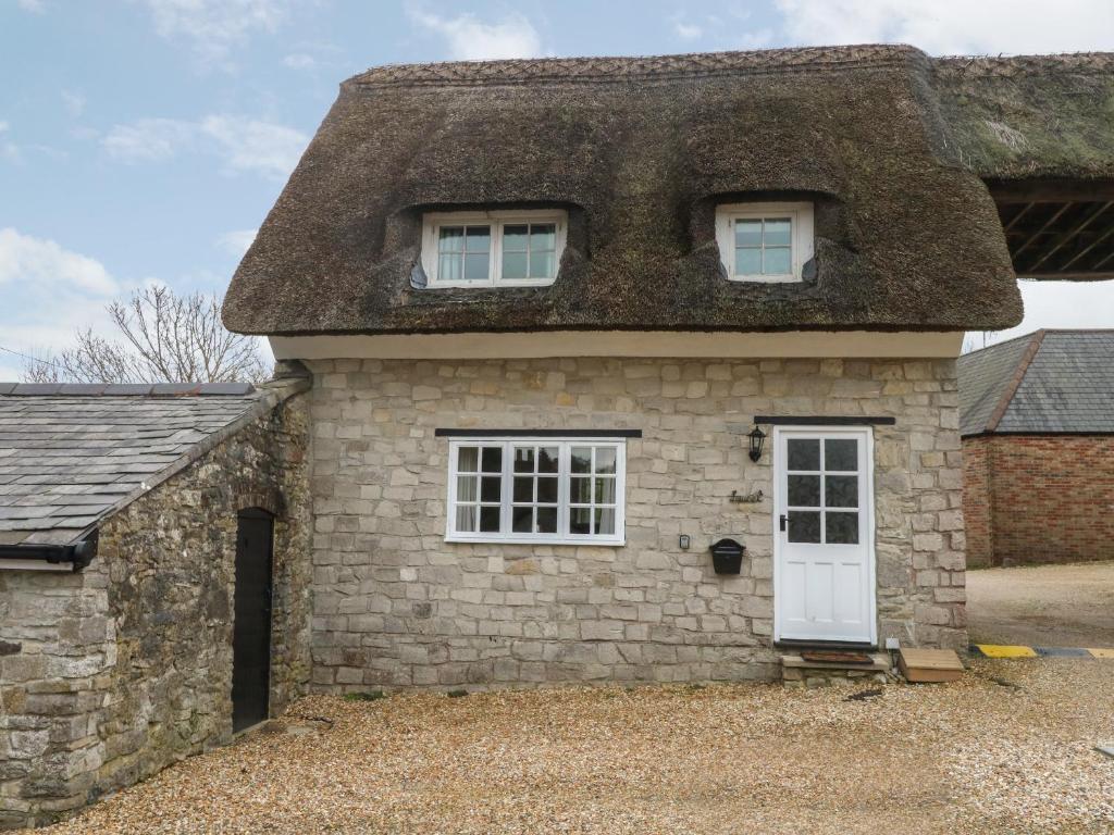 an old stone house with a thatched roof at Laurel Cottage in Weymouth