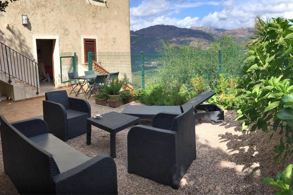 un patio con sofás, sillas y una mesa. en CASA NEPITA sur vue grandiose, en Santa-Lucia-di-Tallano