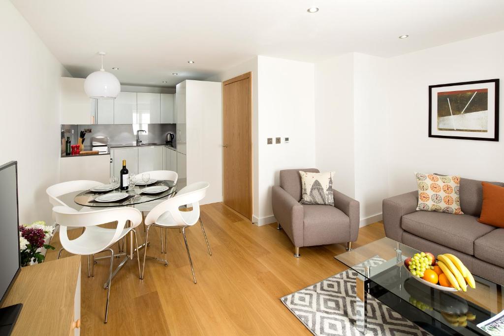 a kitchen and a living room with a table and chairs at Cambric by Aeria Apartments in London