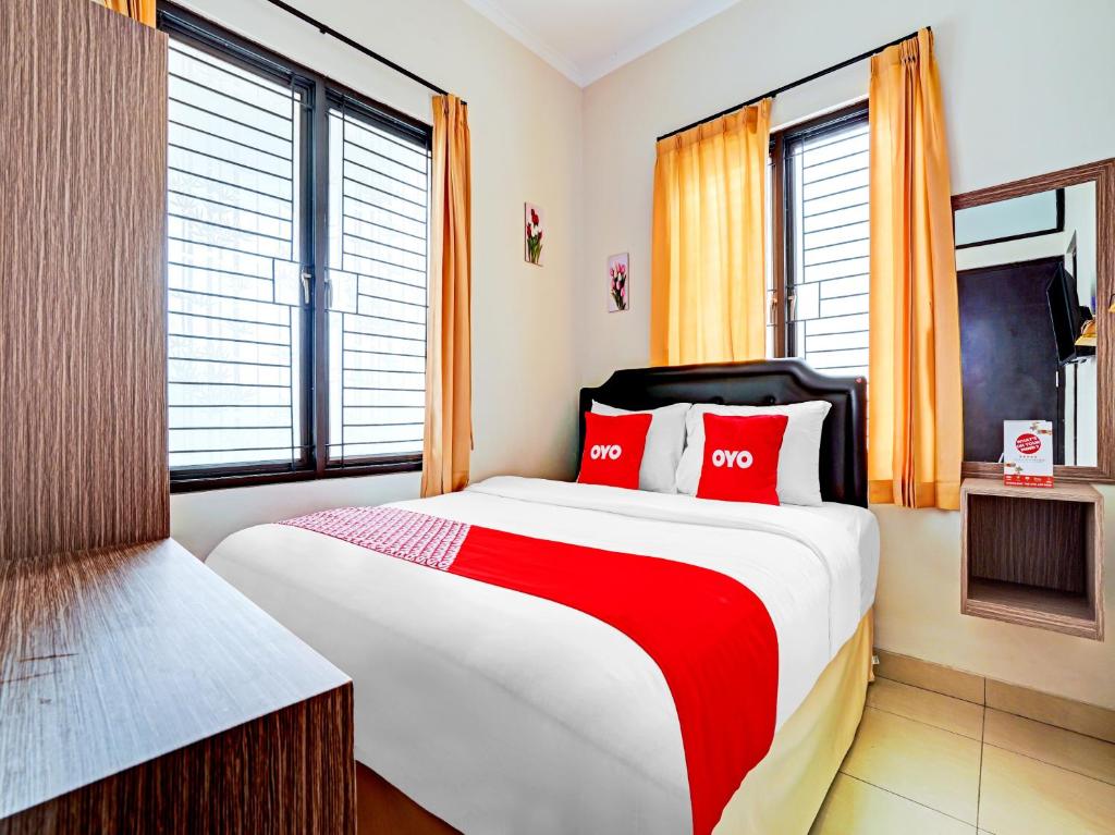 a bedroom with a large bed with red pillows at OYO Life 90211 I-sidji Inn in Karawang