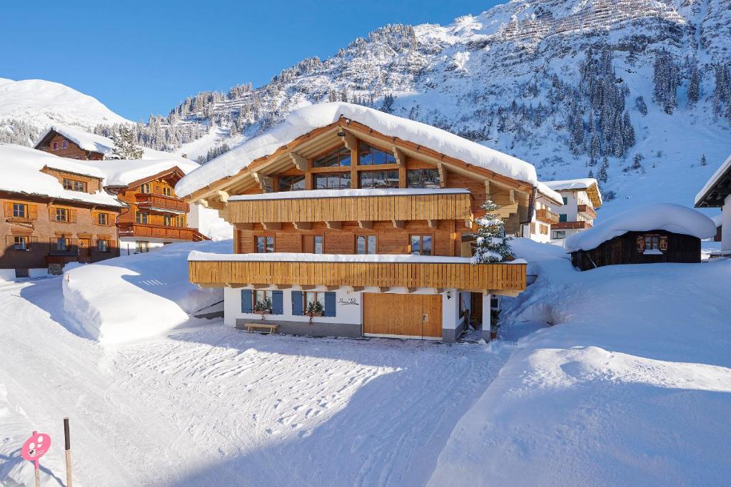 a building covered in snow with a mountain at Appartements Täli in Lech am Arlberg