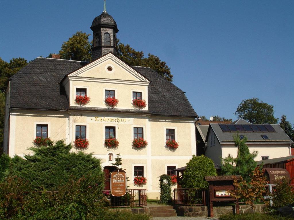 Biały budynek z wieżą zegarową na górze w obiekcie Landhotel Thürmchen w mieście Schirgiswalde