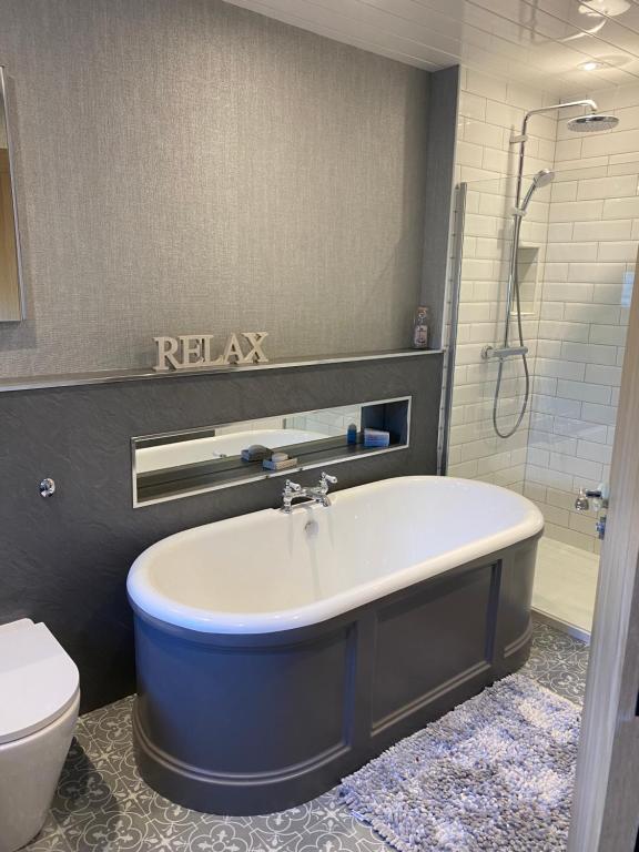 a bathroom with a bath tub and a toilet at NC500, Wick Caithness Holiday Home in Wick