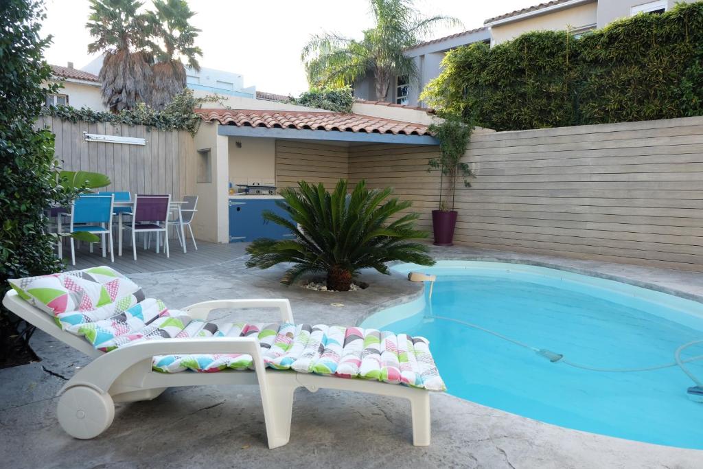 - une piscine avec 2 chaises longues à côté d'une maison dans l'établissement Très bel appartement (40m²) avec piscine privative, à Perpignan