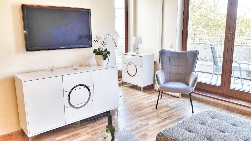 - un salon avec une télévision et une chaise dans l'établissement Apartament Perła Juraty, à Jurata