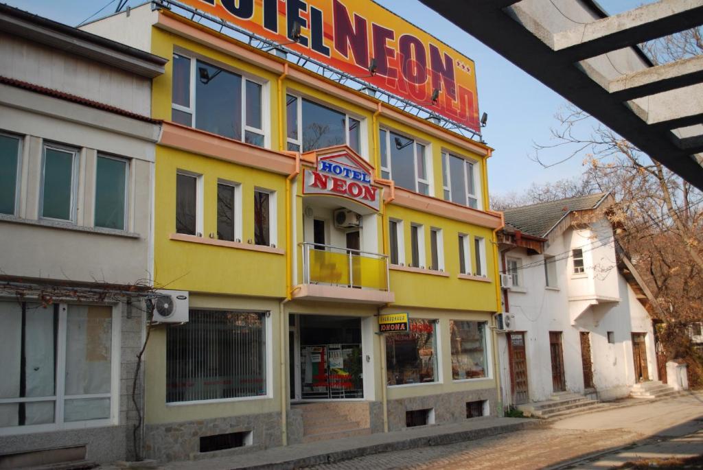 un edificio amarillo con un cartel para una pizzería en Neon Guest Rooms, en Shumen