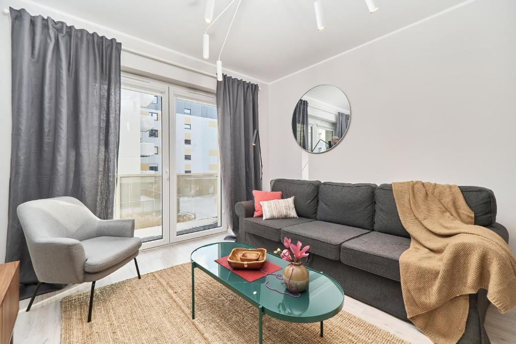 a living room with a couch and a chair and a table at Promenady Green Apartments by Renters in Wrocław