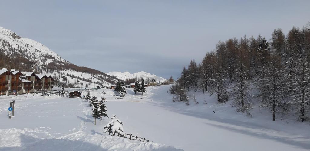 a snow covered mountain with trees and a lodge at Hotel Lago Losetta in Sestriere