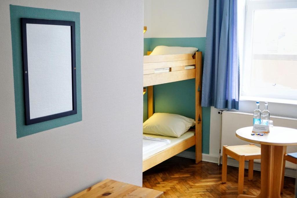 ヘルヌムにあるJugendherberge Hörnumの二段ベッドとテーブルが備わる小さな客室です。
