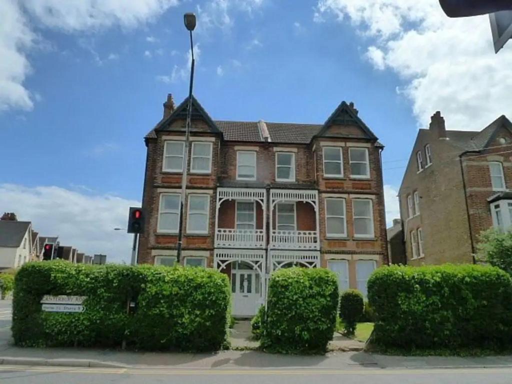 um grande edifício de tijolos com arbustos à frente em Top floor flat with sea view em Herne Bay