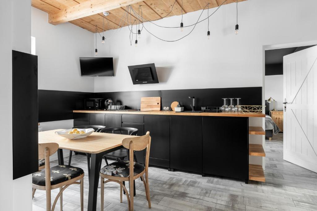 a kitchen with black cabinets and a wooden table and chairs at APARTAMENTY DVOOR1924 in Poronin
