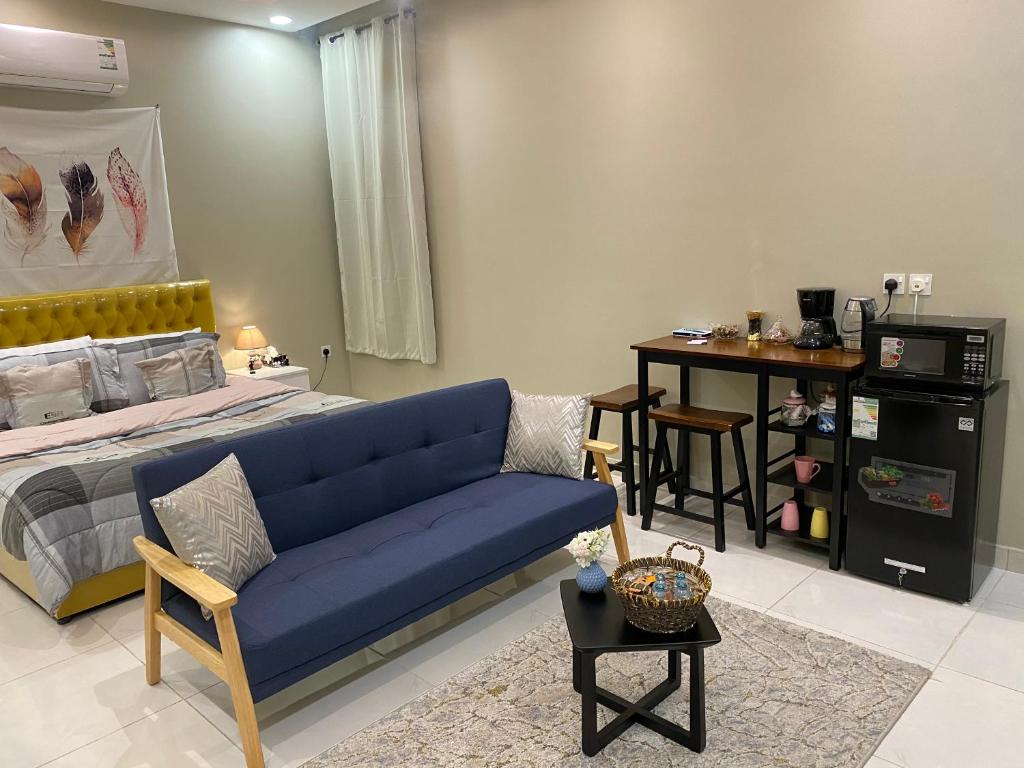 ein Wohnzimmer mit einem blauen Sofa und einem Bett in der Unterkunft S - 369 مقابل الراشد مول in Abha