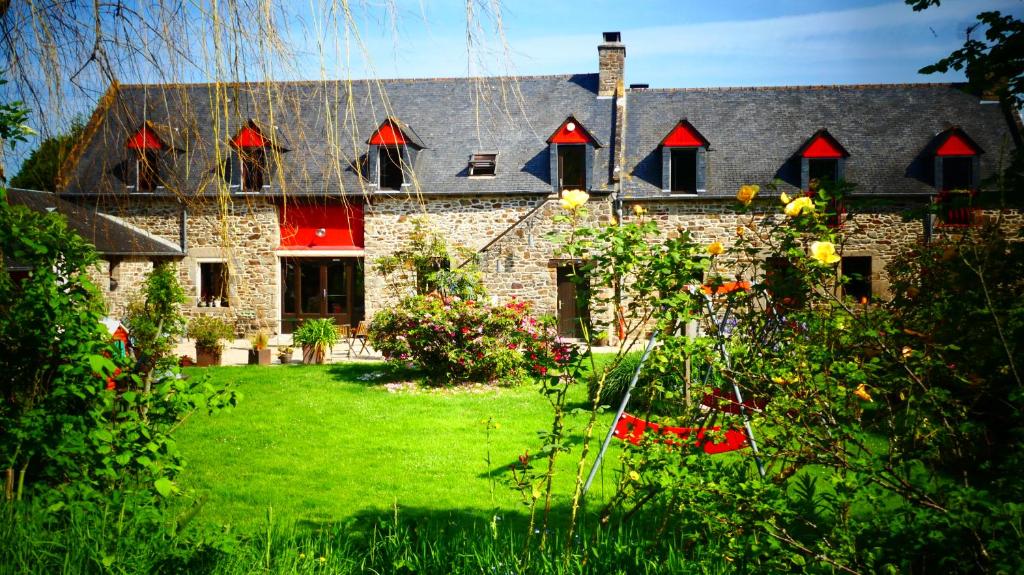 ein Steinhaus mit roten Fenstern und einem Hof in der Unterkunft Auberge de la Chesnaie in Pleudihen