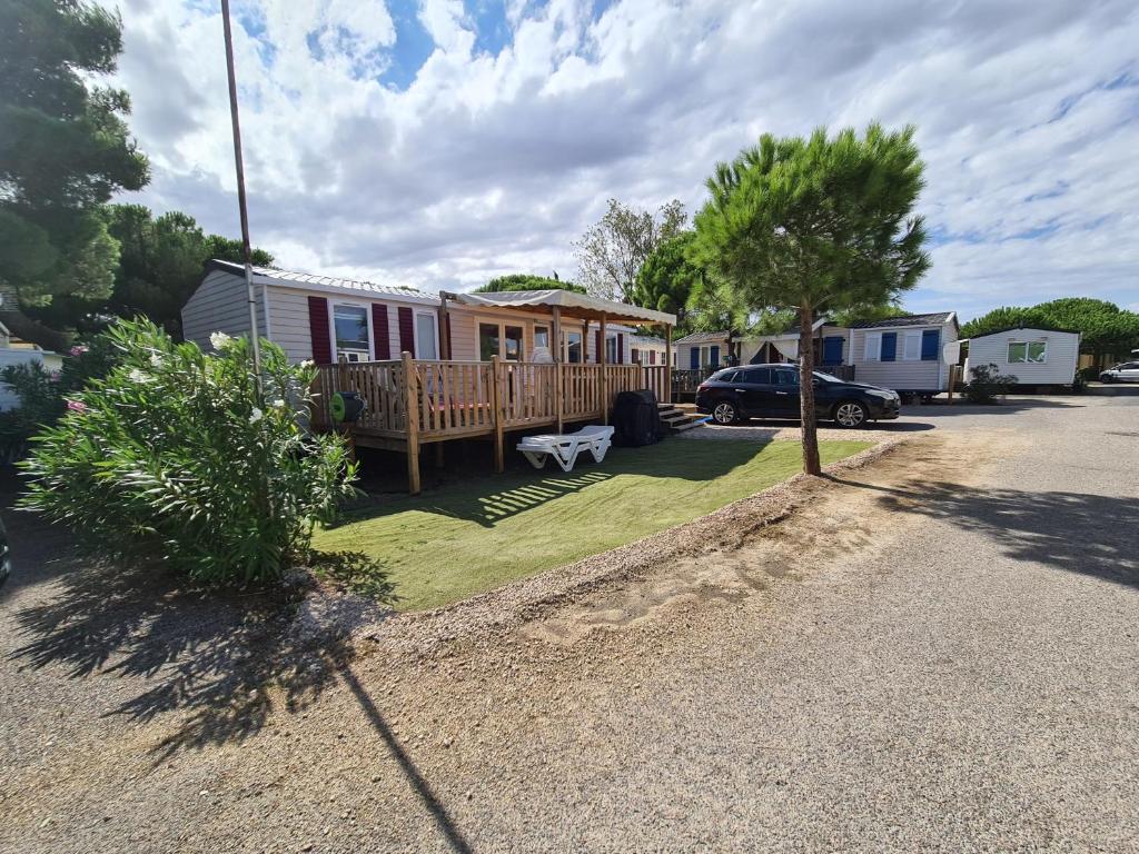 een tiny house met een veranda en een auto geparkeerd op een oprit bij Mobil home Sylvie et Alain in Canet-en-Roussillon