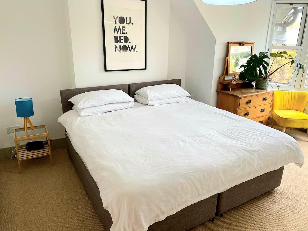um quarto com uma cama grande e lençóis brancos em Upper Rooms Seaford em Seaford