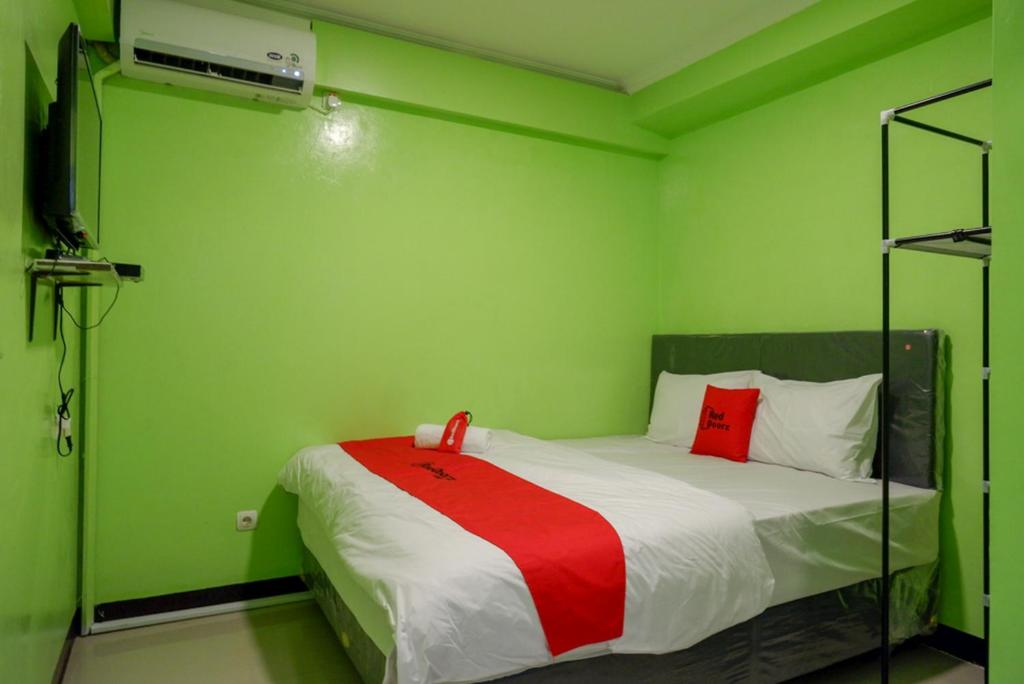um quarto verde com uma cama com um cobertor vermelho em RedDoorz @ Jalan Gatot Subroto Semarang em Kalibanteng-kidul