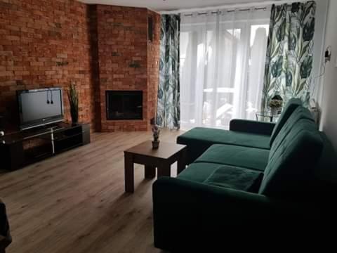 salon z zieloną kanapą i telewizorem w obiekcie Apartamenty Pod Sosnami Ostróda Międzylesie 6os w Ostródzie