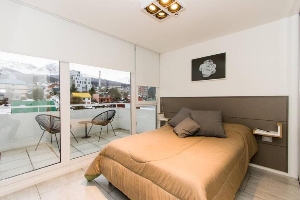 a bedroom with a bed and a balcony at Temporales Ushuaia - Bahia loft in Ushuaia