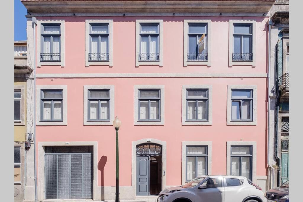 un edificio rosa con un coche aparcado delante de él en BOUTIQUE Rentals- Art & Charm Apt w/ balcony & garage en Oporto