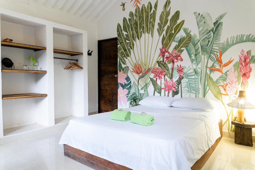 a bedroom with a white bed with a floral mural on the wall at Reserva Biologica Caoba in Bonda