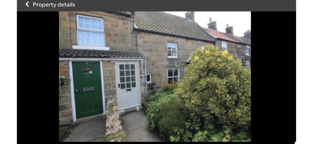 a brick house with a green door and a yard at Carlton Cottage, Castleton in Castleton