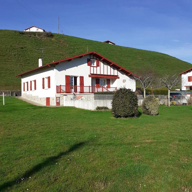 a white house with a green hill in a field at UR ONDOAN - Appartement Saint Pée sur Nivelle in Saint-Pée-sur-Nivelle