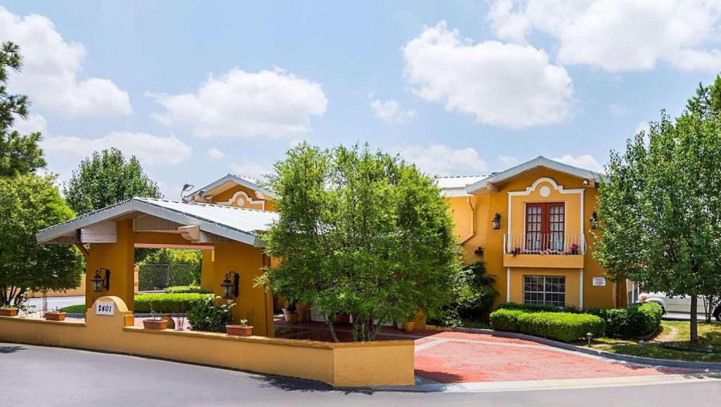 Una casa amarilla con un árbol delante. en Magnuson Hotel Little Rock South en Little Rock