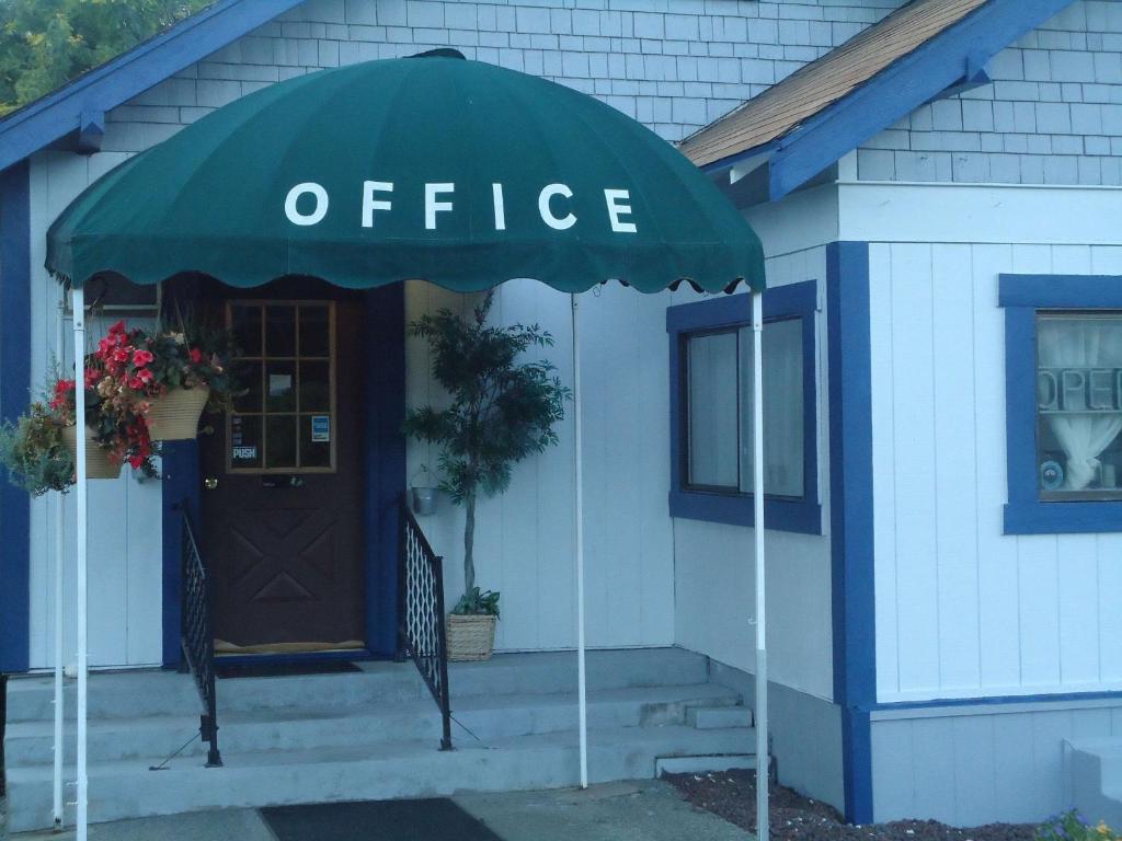Blue Mountain Motel في Okanogan: مبنى فيه مظله امام مكتب