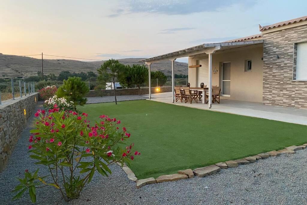 a backyard with a green lawn and a house at Havouli Sunset Villa in Moudhros