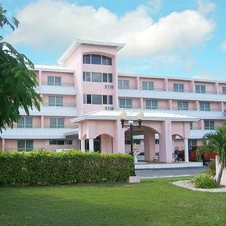 a large pink building with a palm tree in front of it at Castaways Resort and Suites in Freeport