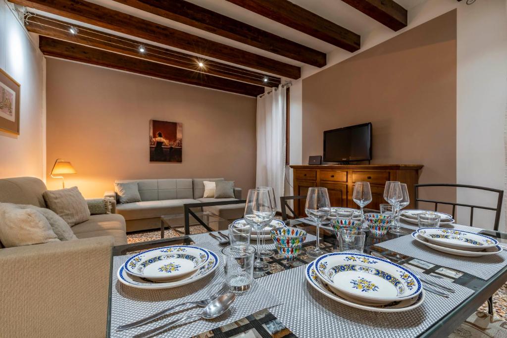 uma sala de estar com uma mesa com pratos e copos em San Marco - 2 bedrooms with lift em Veneza