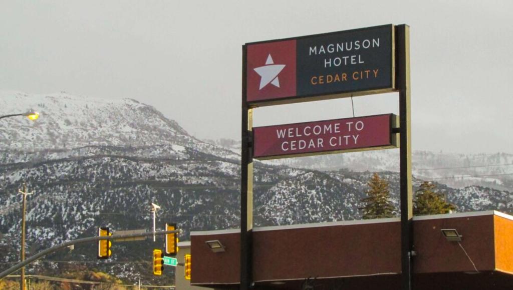 a sign for a hotel and a welcome to gari city at Magnuson Cedar City in Cedar City