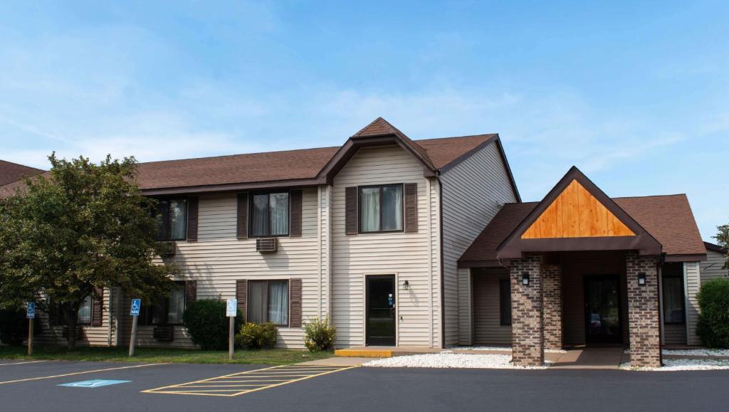 een groot huis met een bruin dak bij Magnuson Hotel Country Inn in Ishpeming