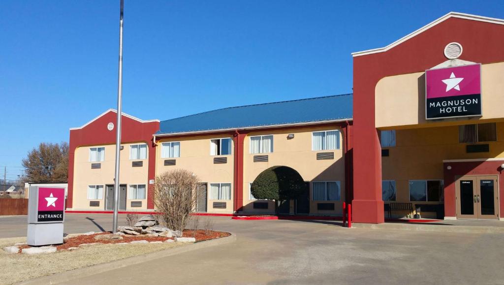 un bâtiment d'hôtel avec un panneau devant lui dans l'établissement Magnuson Hotel Sand Springs – Tulsa West, à Sand Springs