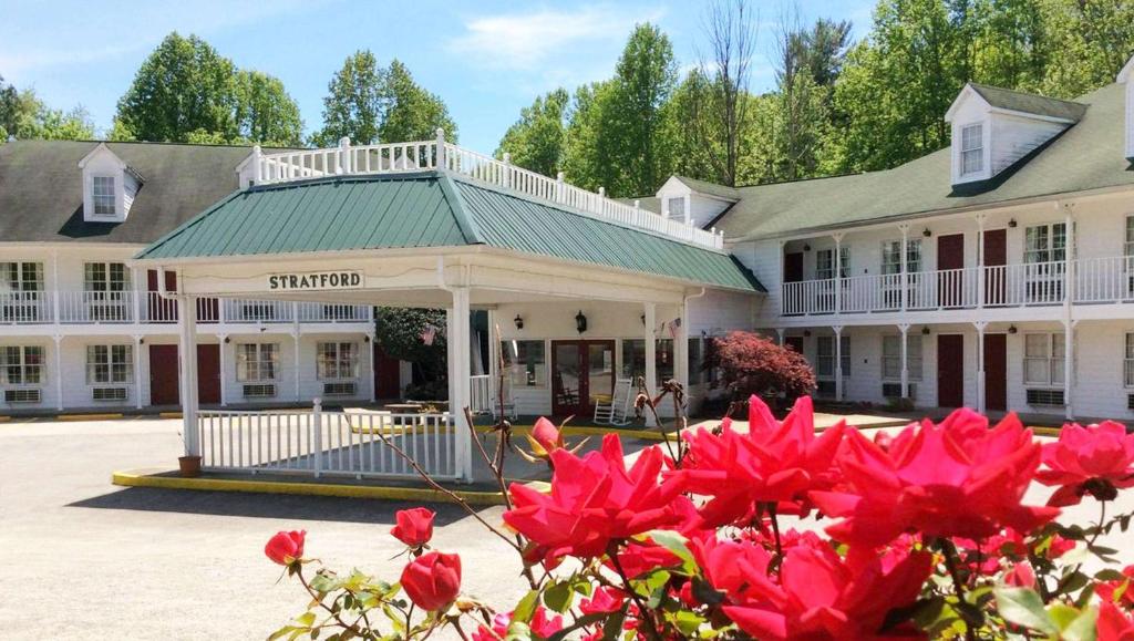 un gran edificio blanco con flores rojas delante en Stratford Motor Inn East Ellijay en East Ellijay