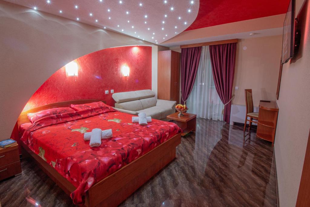 een slaapkamer met een groot rood bed en een bank bij Villa Dislievski in Ohrid