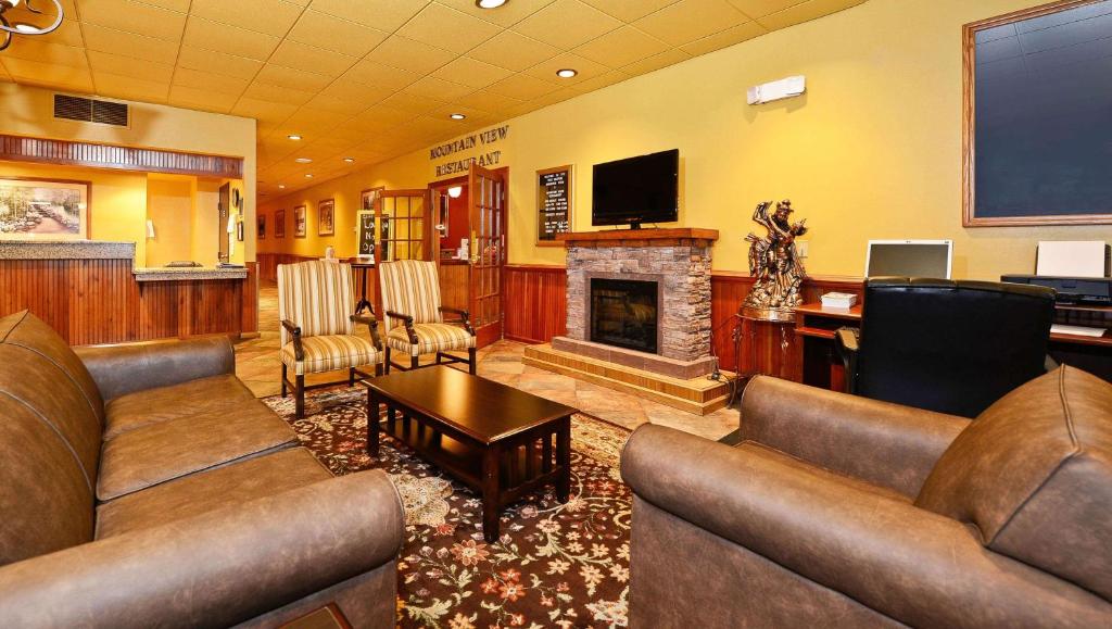 a living room with leather couches and a fireplace at Magnuson Hotel Mountain View in Covington
