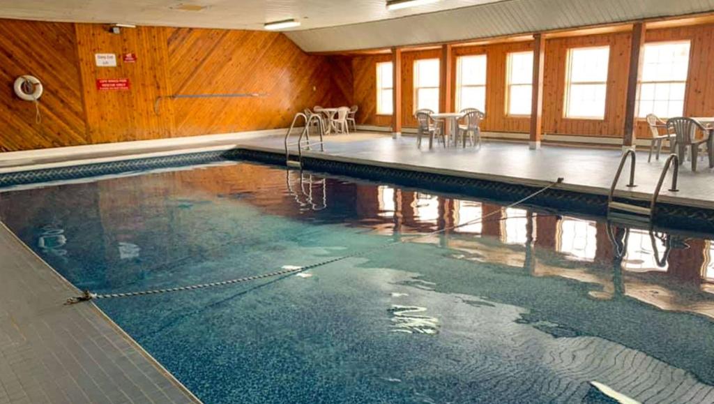 una piscina con mesas y sillas en un edificio en Traveller's Inn Prince Edward Island, en Summerside